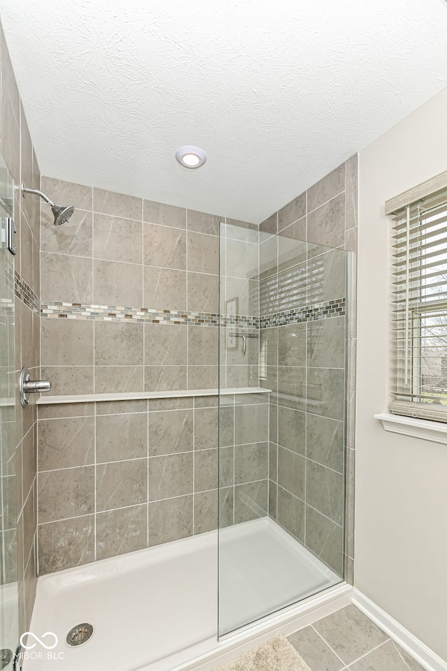 full bathroom with a shower stall, baseboards, tile patterned floors, and a textured ceiling