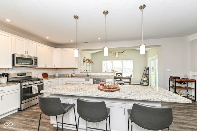 kitchen featuring dark wood-style flooring, a sink, white cabinets, appliances with stainless steel finishes, and backsplash