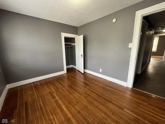 unfurnished bedroom featuring dark wood-style floors, baseboards, a closet, and a textured ceiling