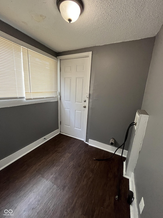 unfurnished room with baseboards, a textured ceiling, and dark wood-style floors