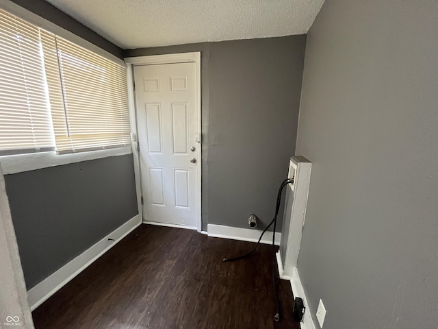 interior space with baseboards, a textured ceiling, and dark wood-style flooring