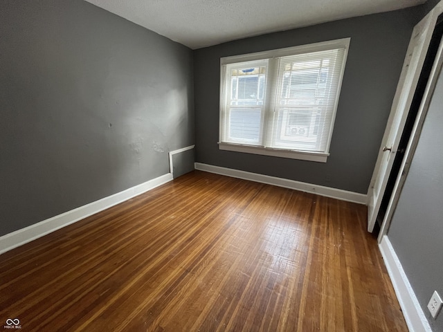 unfurnished bedroom featuring baseboards and dark wood-style flooring