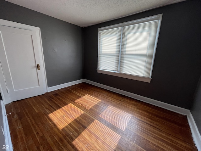 unfurnished room featuring wood finished floors, baseboards, and a textured ceiling