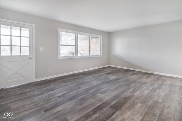 unfurnished living room featuring a healthy amount of sunlight, dark wood-style flooring, and baseboards