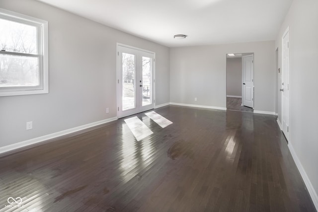 spare room with dark wood finished floors, french doors, and baseboards