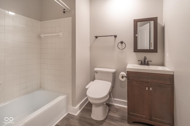 bathroom featuring vanity, wood finished floors, baseboards, bathtub / shower combination, and toilet