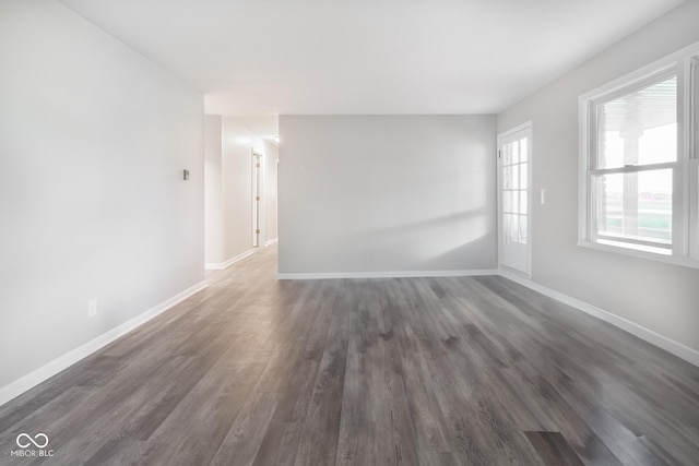 unfurnished room featuring baseboards and dark wood-style floors