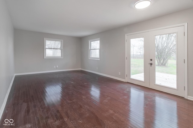 spare room featuring dark wood finished floors, french doors, and baseboards