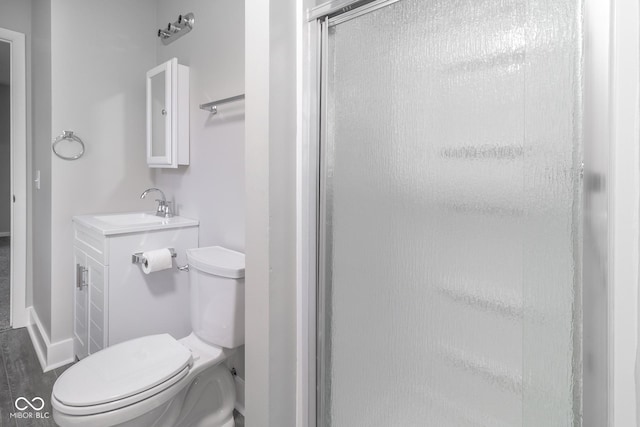 bathroom featuring vanity, toilet, baseboards, and a stall shower