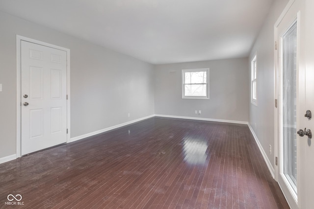 empty room featuring baseboards and dark wood-style flooring