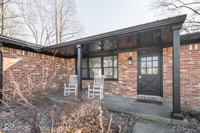 property entrance featuring covered porch and brick siding