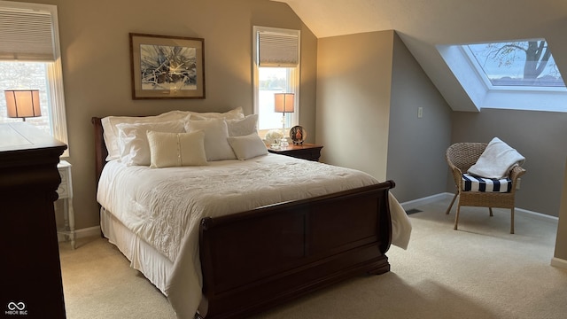 bedroom featuring light carpet, multiple windows, and vaulted ceiling with skylight