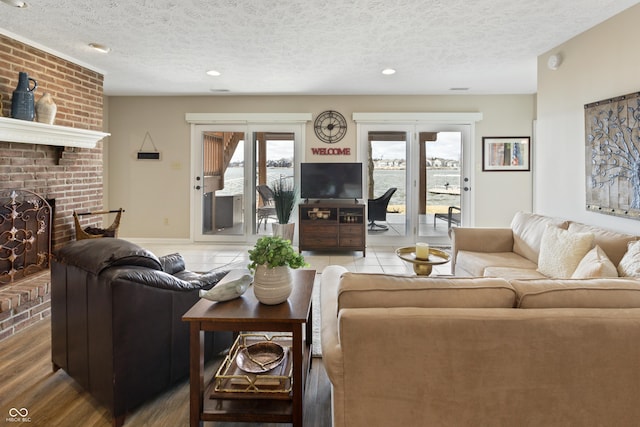 living area with baseboards, a textured ceiling, wood finished floors, and a fireplace