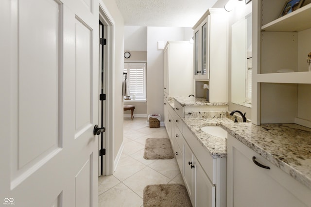 bathroom featuring vanity, baseboards, tile patterned flooring, and a textured ceiling