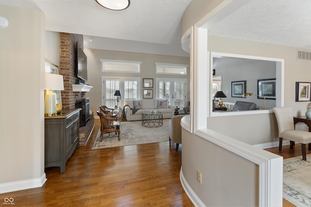 interior space with baseboards, wood finished floors, visible vents, and a textured ceiling