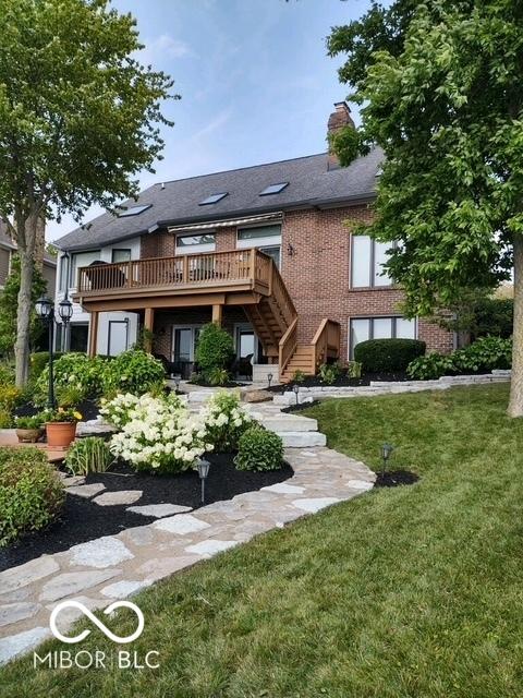 back of property with brick siding, stairway, a chimney, a yard, and a deck