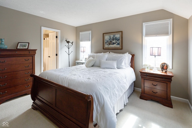 bedroom with vaulted ceiling, light colored carpet, baseboards, and multiple windows