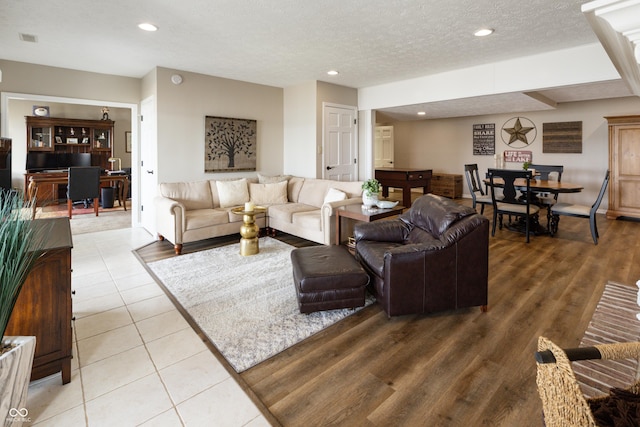 living room featuring light tile patterned floors, visible vents, a textured ceiling, and recessed lighting