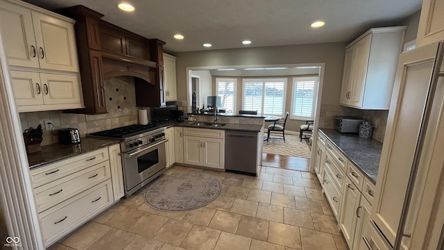 kitchen with high end stainless steel range, a sink, tasteful backsplash, a peninsula, and dishwashing machine