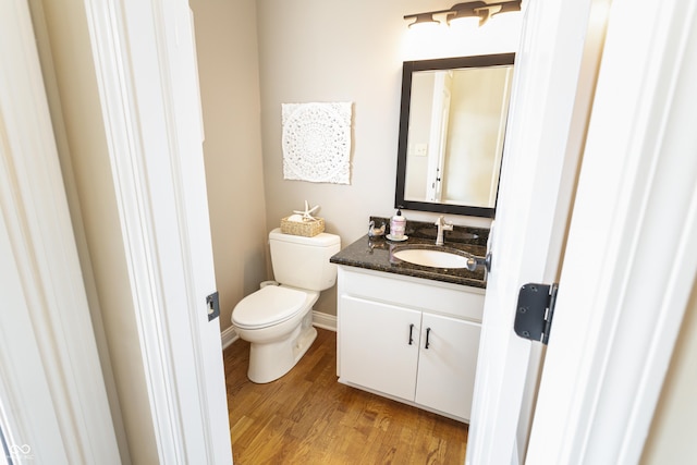 bathroom featuring baseboards, toilet, wood finished floors, and vanity