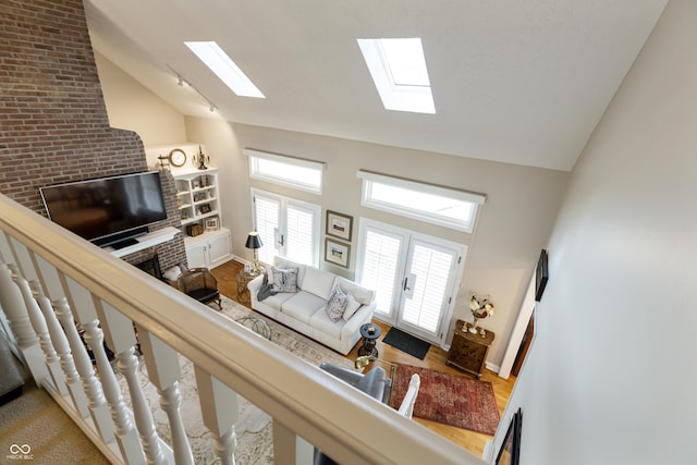 living area featuring baseboards, high vaulted ceiling, a healthy amount of sunlight, and a skylight