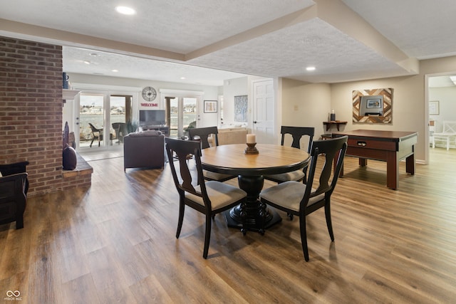 dining space with recessed lighting, a textured ceiling, a wood stove, and wood finished floors