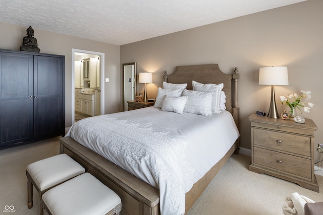 bedroom with a textured ceiling, connected bathroom, and light carpet