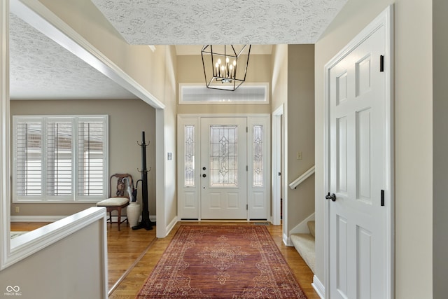 entrance foyer with stairway, baseboards, light wood finished floors, and a chandelier