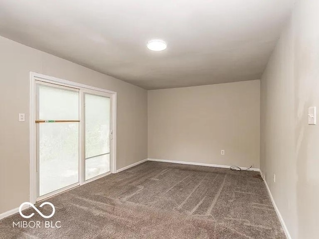 unfurnished room with dark carpet and baseboards