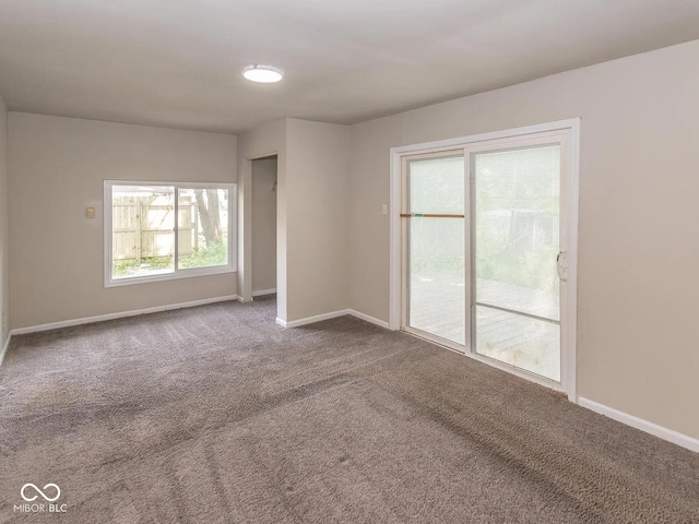 carpeted empty room featuring baseboards