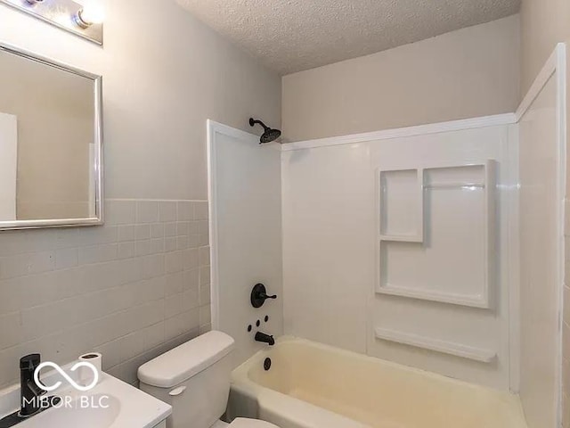 bathroom with tile walls, shower / bath combination, toilet, and a textured ceiling