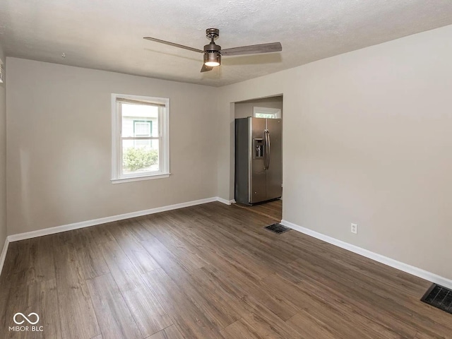 unfurnished room featuring visible vents, baseboards, and dark wood finished floors