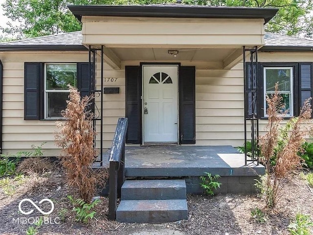 property entrance with covered porch and roof with shingles