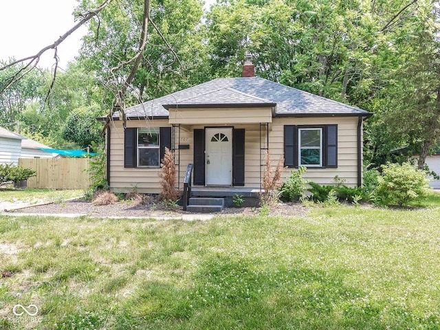 bungalow featuring a front yard, fence, roof with shingles, and a chimney