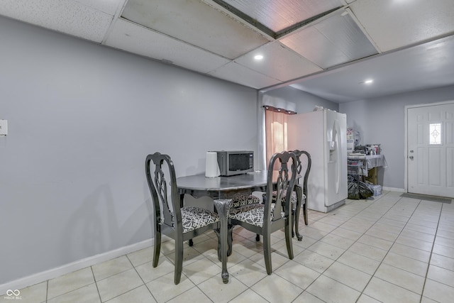 dining area with light tile patterned floors, baseboards, and a drop ceiling