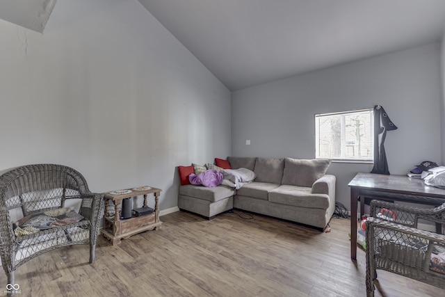 living area featuring baseboards, lofted ceiling, and wood finished floors