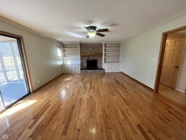 unfurnished living room with built in features, a ceiling fan, baseboards, light wood-style flooring, and ornamental molding