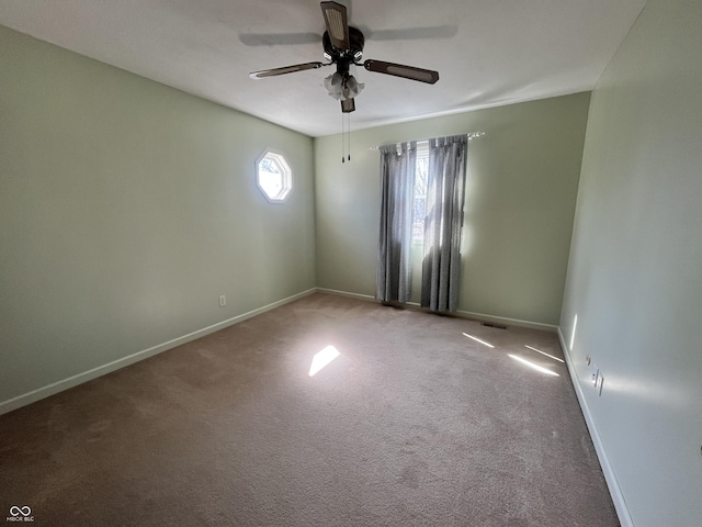 carpeted spare room featuring visible vents, a ceiling fan, and baseboards