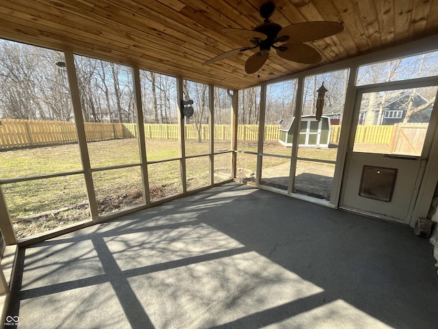 unfurnished sunroom with wooden ceiling, a healthy amount of sunlight, and ceiling fan