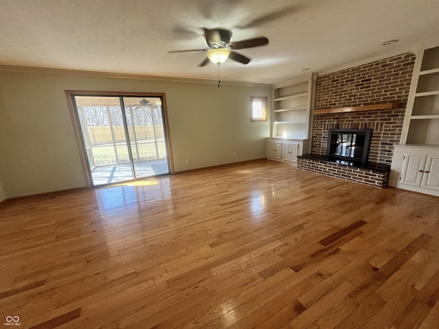 unfurnished living room featuring a wealth of natural light, built in shelves, wood finished floors, and crown molding