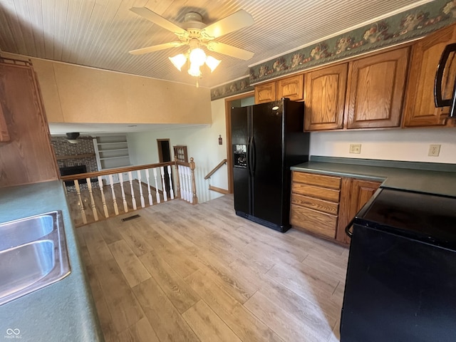 kitchen with a sink, black appliances, light wood-style flooring, and brown cabinetry