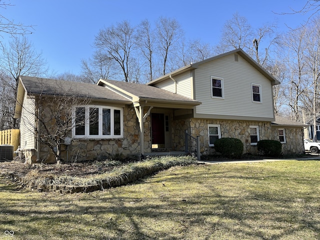 tri-level home featuring stone siding, central AC unit, a front lawn, and roof with shingles