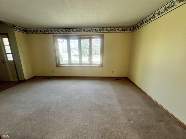 carpeted empty room featuring baseboards