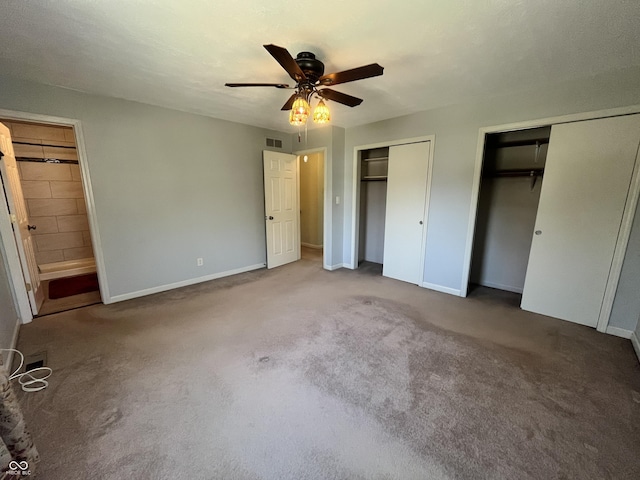 unfurnished bedroom featuring baseboards, visible vents, two closets, and carpet floors