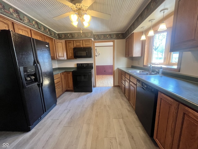 kitchen with brown cabinetry, a ceiling fan, light wood-style flooring, a sink, and black appliances