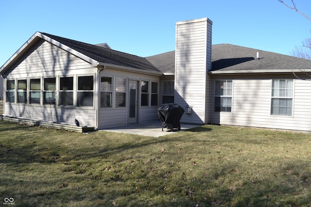 rear view of house with a yard, roof with shingles, a chimney, and a patio area