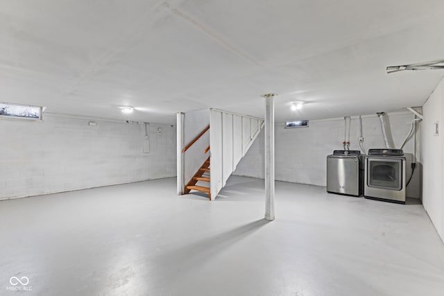 finished below grade area featuring stairway, washing machine and dryer, and concrete block wall