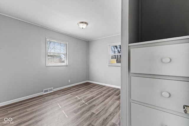 empty room with visible vents, baseboards, and wood finished floors