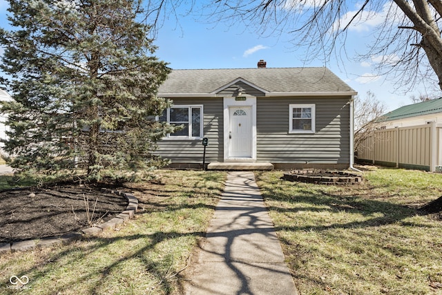 bungalow-style house featuring a front yard, roof with shingles, a chimney, and fence