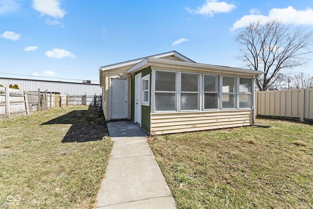 view of front of home featuring a fenced backyard, a front yard, and a sunroom